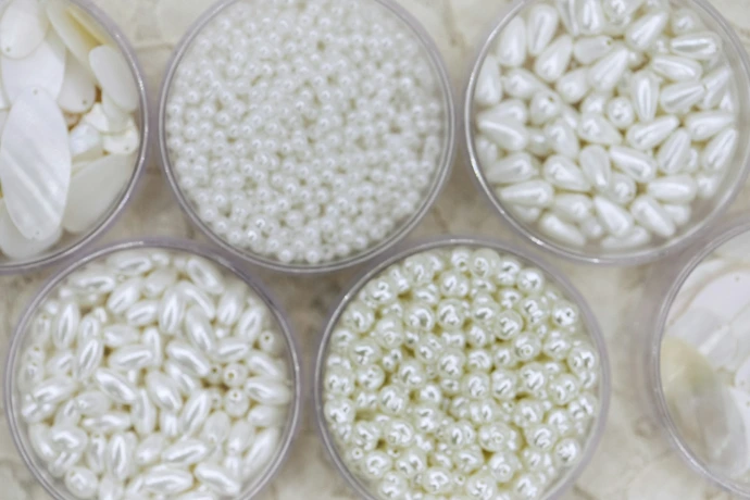 Different types of white beads are in clear containers.